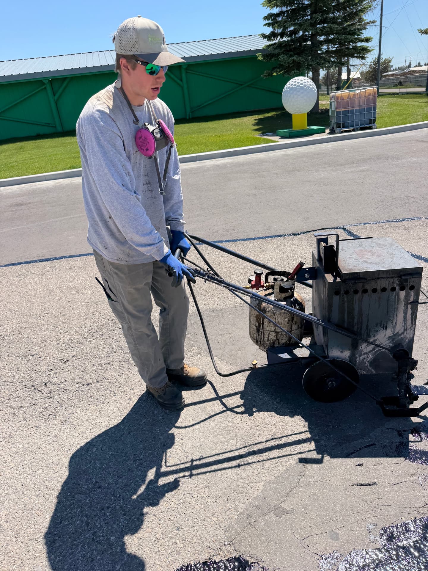 Close-up of asphalt crack sealing equipment being operated on a Calgary office lot