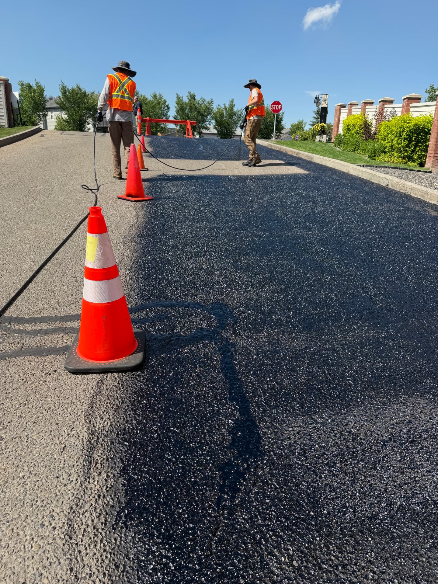 Crew applying hot-pour crack sealant to a Calgary roadway behind traffic cones