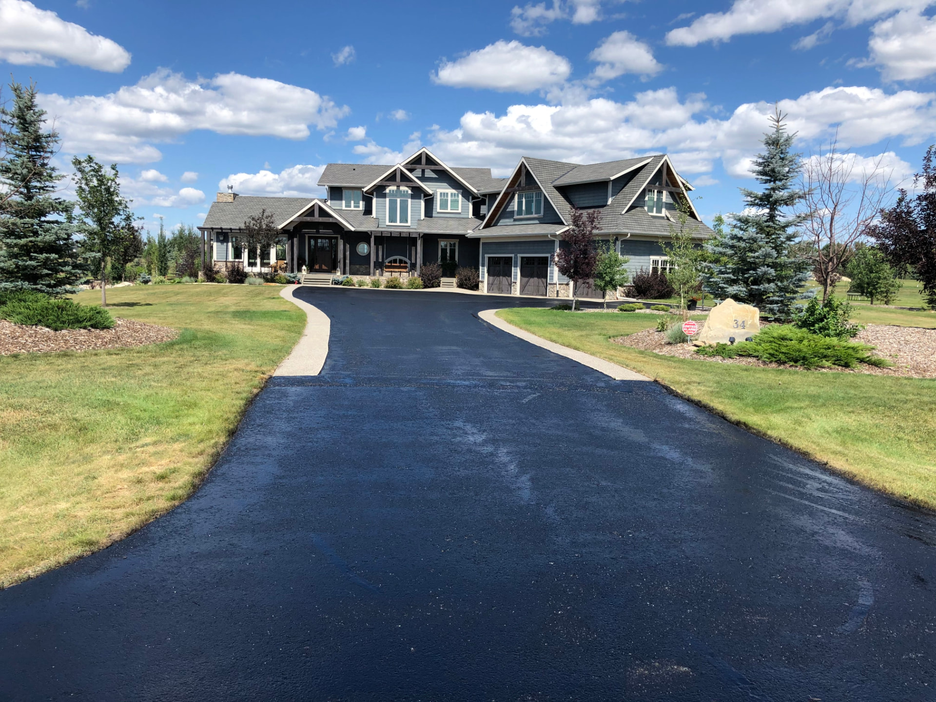 The same driveway after professional sealing, deep black with clean edges