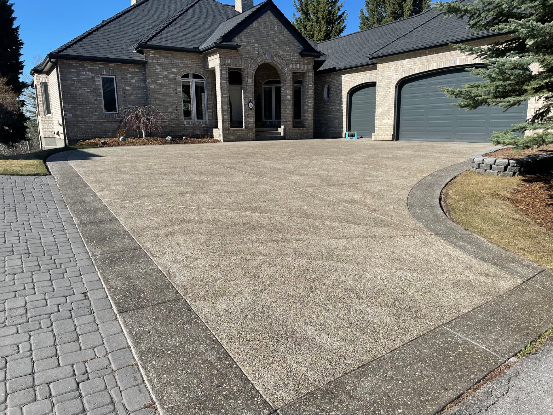 Faded grey asphalt driveway with cracking before sealing